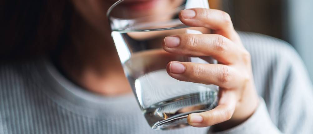 Frau trinkt aus Wasserglas.