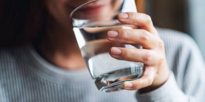 Frau trinkt aus Wasserglas.