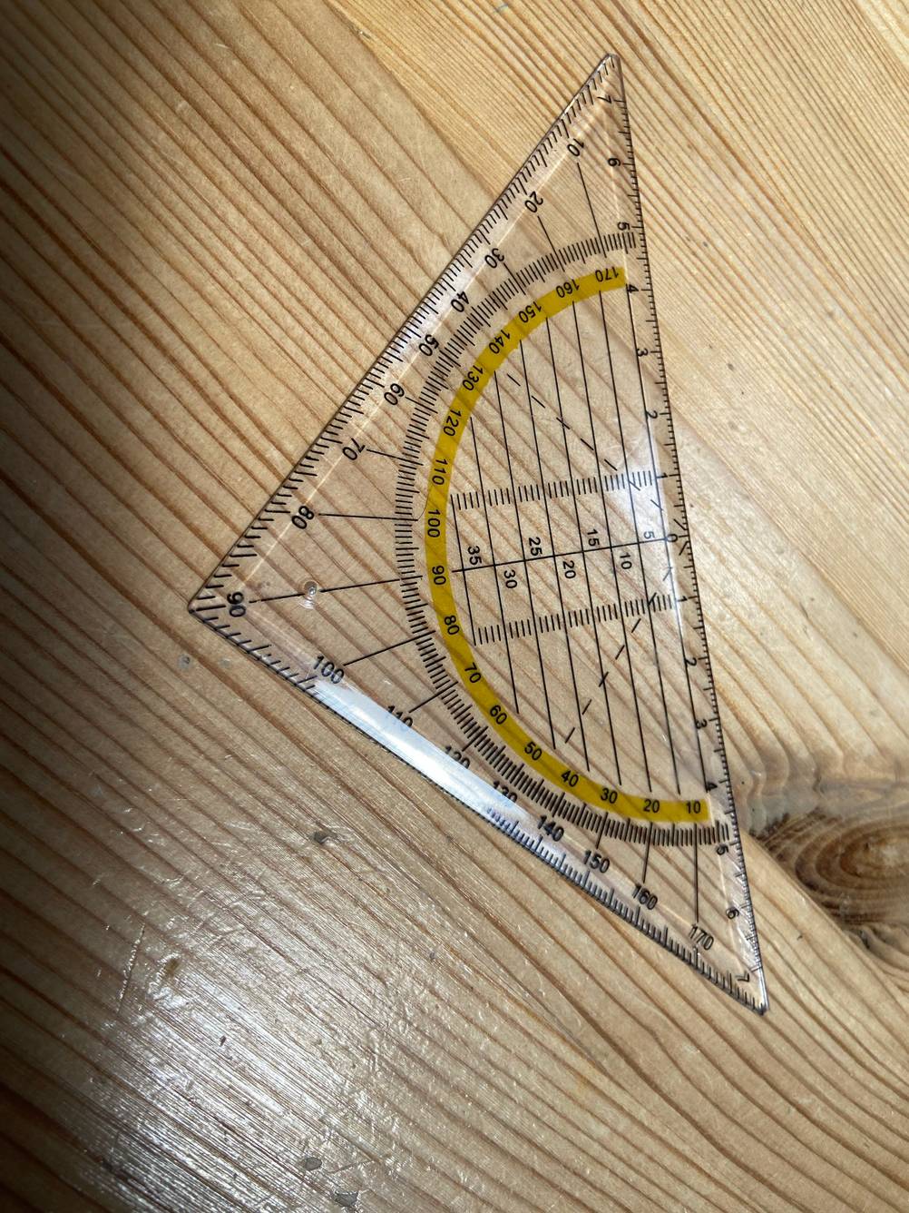 Auf einem Holztisch liegt ein Geodreieck im Test.