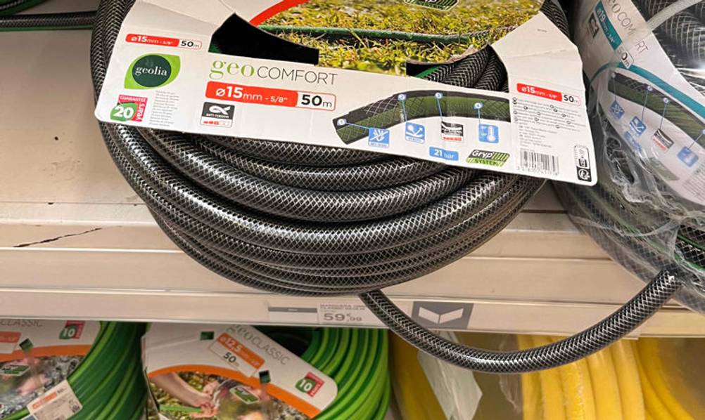 3/4-Zoll-Gartenschlauch im Test: ein schwarzes Modell der Marke Geolia inklusive Verpackung in einem Verkaufsregal mit weiteren Gartenschläuchen verschiedenster Größe und Farbe.