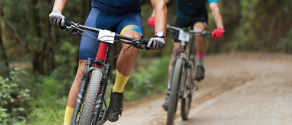 Fahrradhandschuhe-Erwachsene-Test: Zwei Mountainbikefahrer fahren hintereinander; beide tragen Radfahr-Bekleidung und Fahrradhandschuhe.