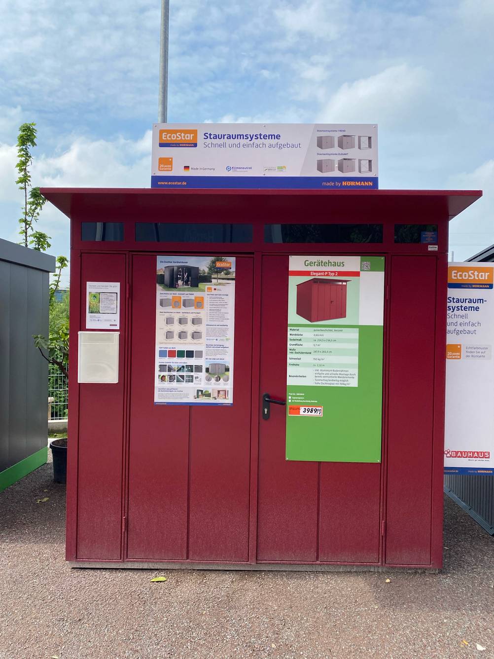 Ein getestetes Gerätehaus aus Metall von vorne in einer Verkaufsfläche mit angebrachten Informationstafeln.
