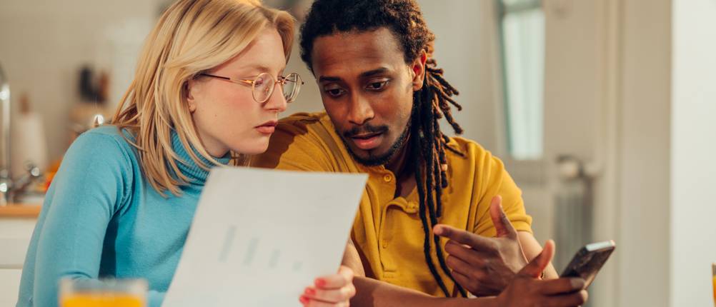 Geräteversicherung im Vergleich: Ein Paar recherchiert und vergleicht Konditionen am Schreibtisch.