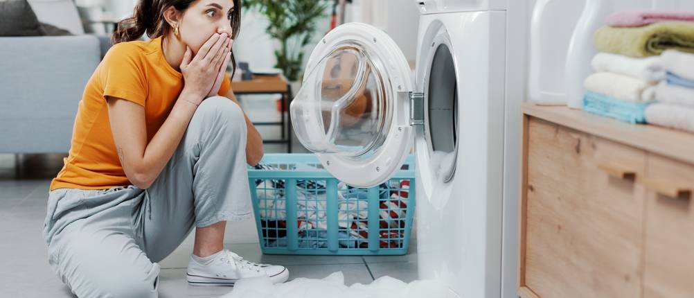 Geräteversicherungen im Vergleich: Eine junge Frau registriert einen Schaden an ihrer Waschmaschine.