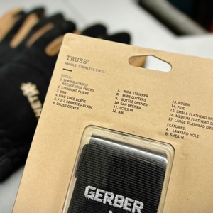 Die Rückseite der Verpackung des Gerber Truss Multitools listet die 17 enthaltenen Werkzeuge auf, wie Drahtschneider, Säge und Schraubendreher. Der schwarze Stoffholster mit dem Gerber-Logo ist teilweise zu sehen.