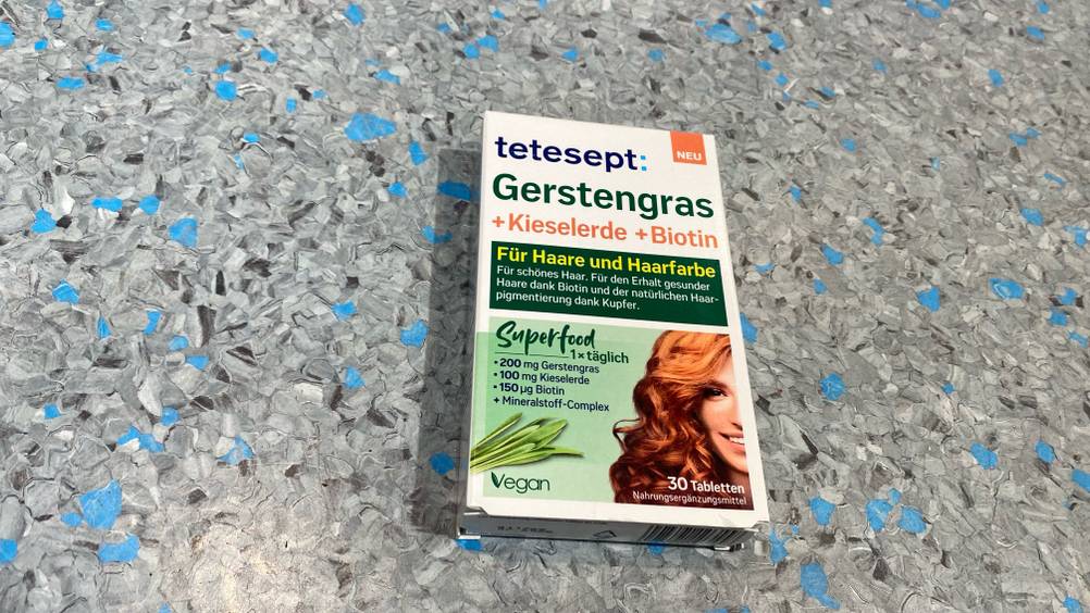 Boden einer Packung der getesteten Gerstengras-Kapseln auf einer grau-blauen Fläche.