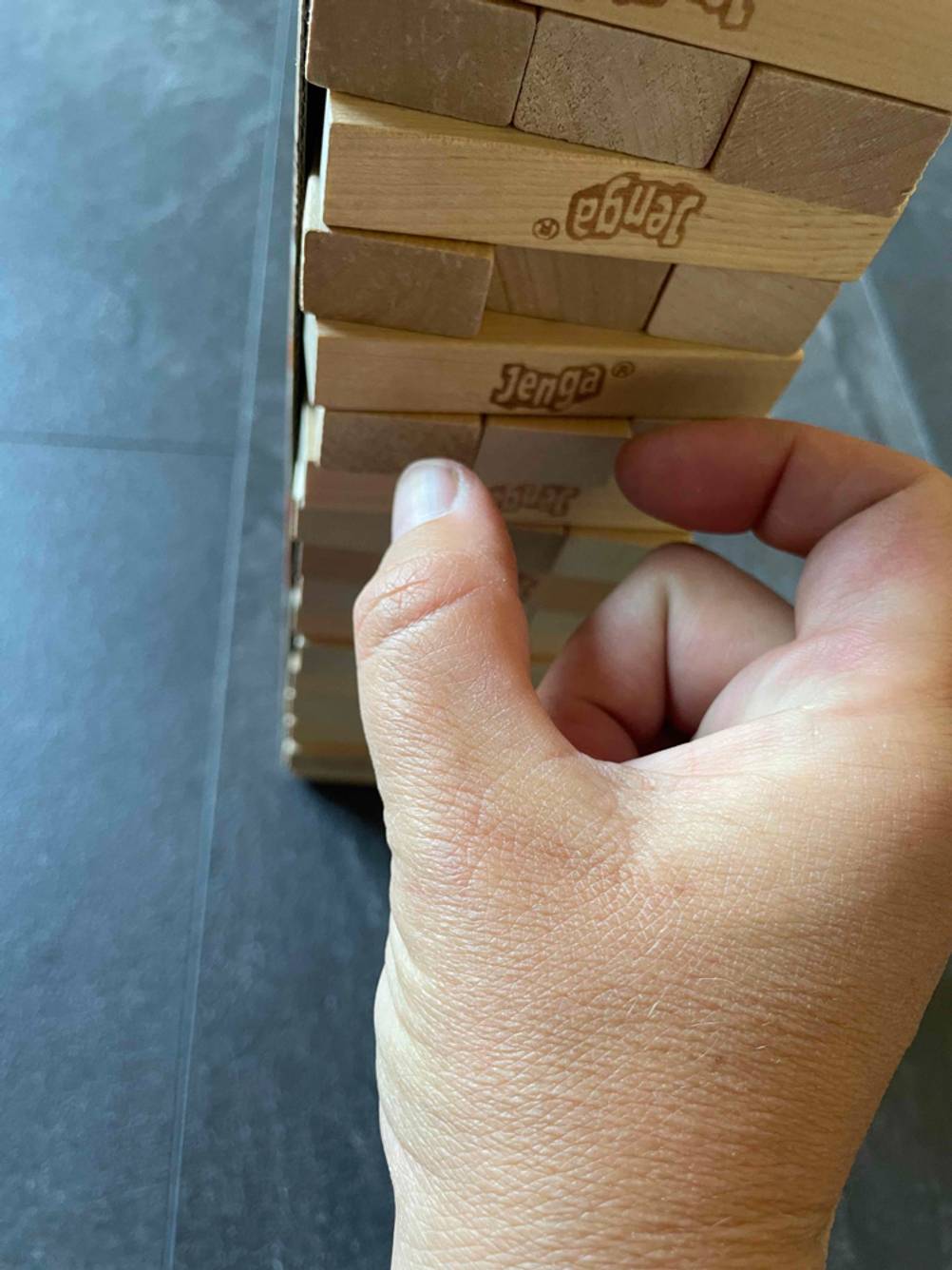 Geschicklichkeitsspiele-Test: Eine Hand versucht einen Stein aus einem Jengaturm zu ziehen.