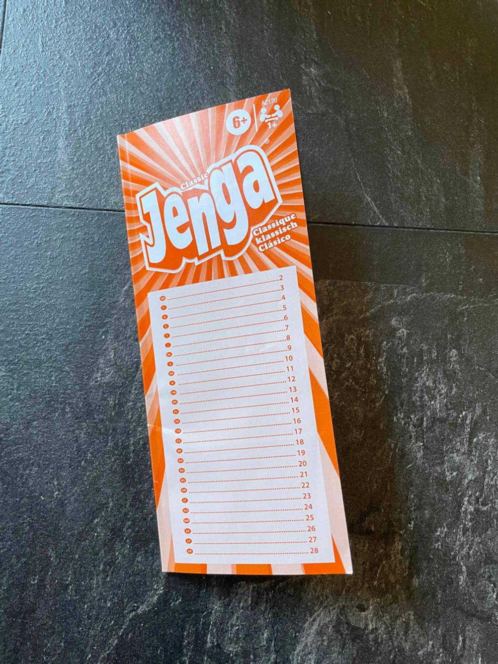 Geschicklichkeitsspiele getestet: Die Bedienungsanleitung von Jenga auf einer dunklen Fläche.