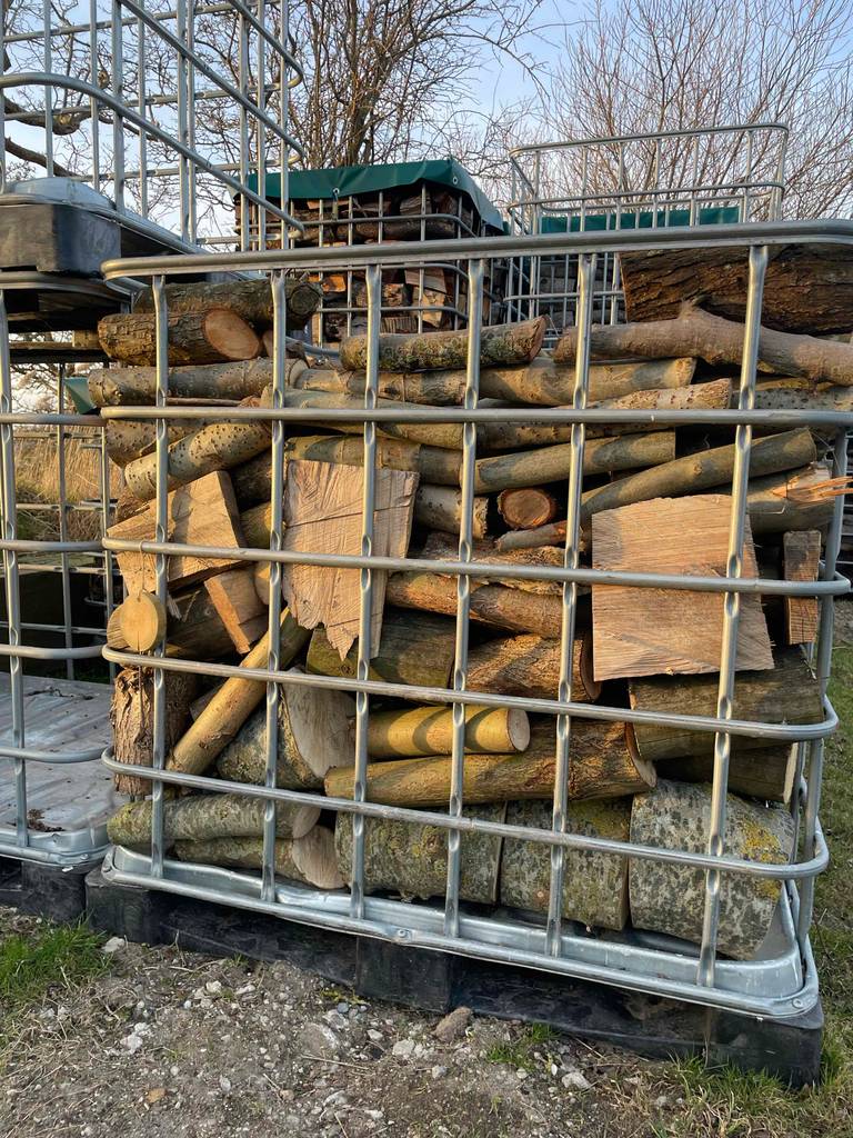 Im Test: Kaminholz befindet sich in einem Gitter-Container im Außenbereich.