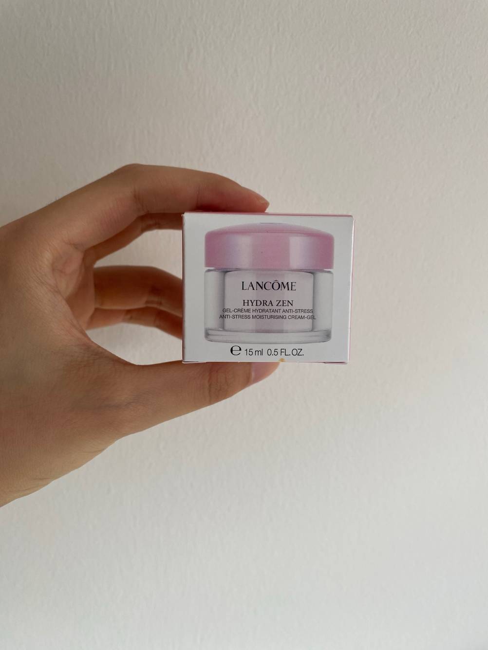 Im Test: Eine Hand hält eine Originalverpackung einer Gesichtscreme vor eine helle Wand.