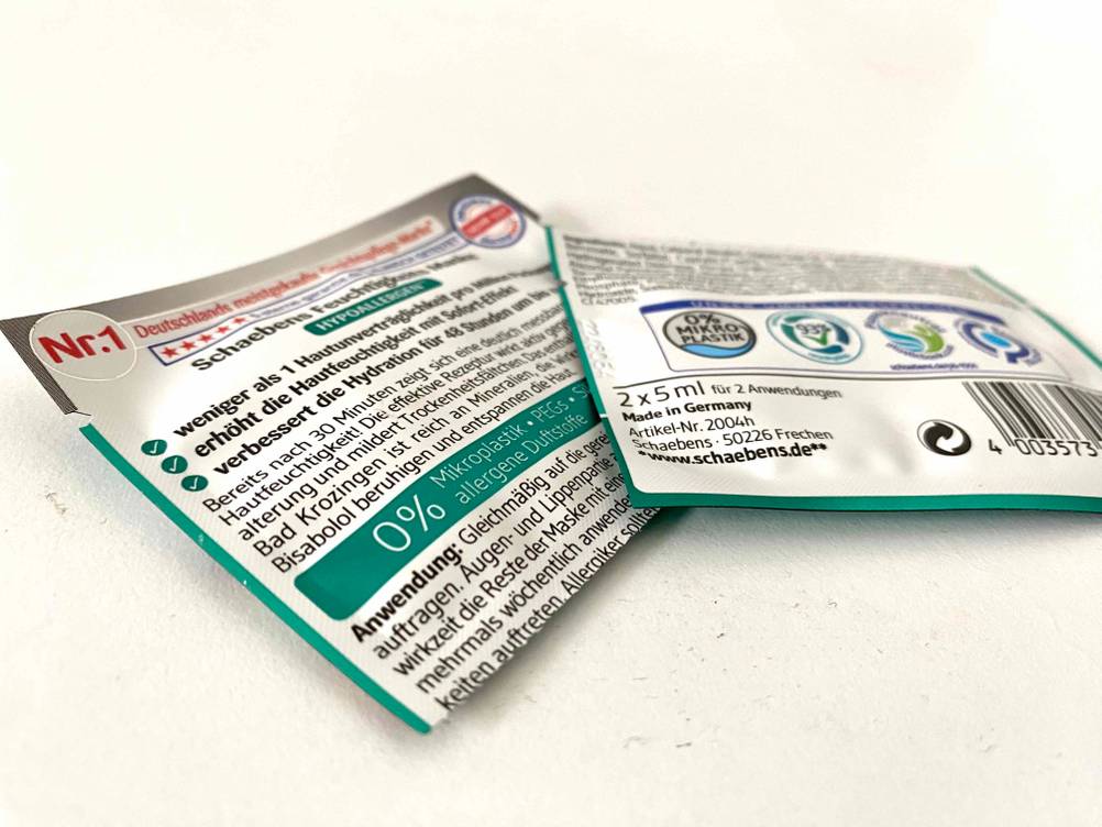 Eine Packung der getesteten Gesichtsmaske geteilt mit der Rückseite nach oben auf einer hellen Fläche.