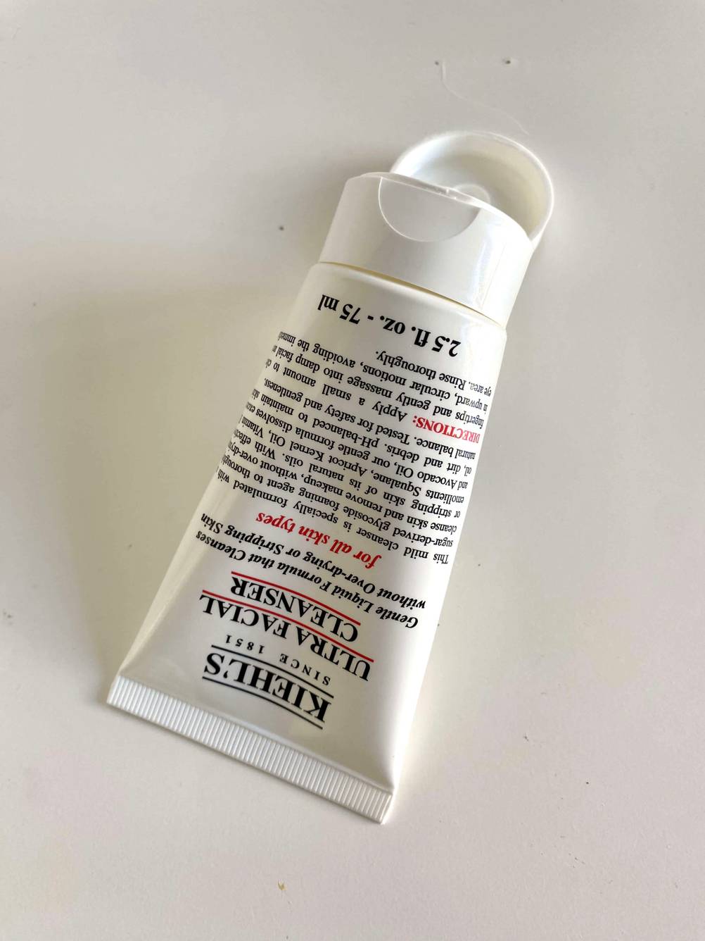 Gesichtsreinigung im Test: Eine Tube liegt auf einer hellen Fläche mit geöffnetem Verschluss.