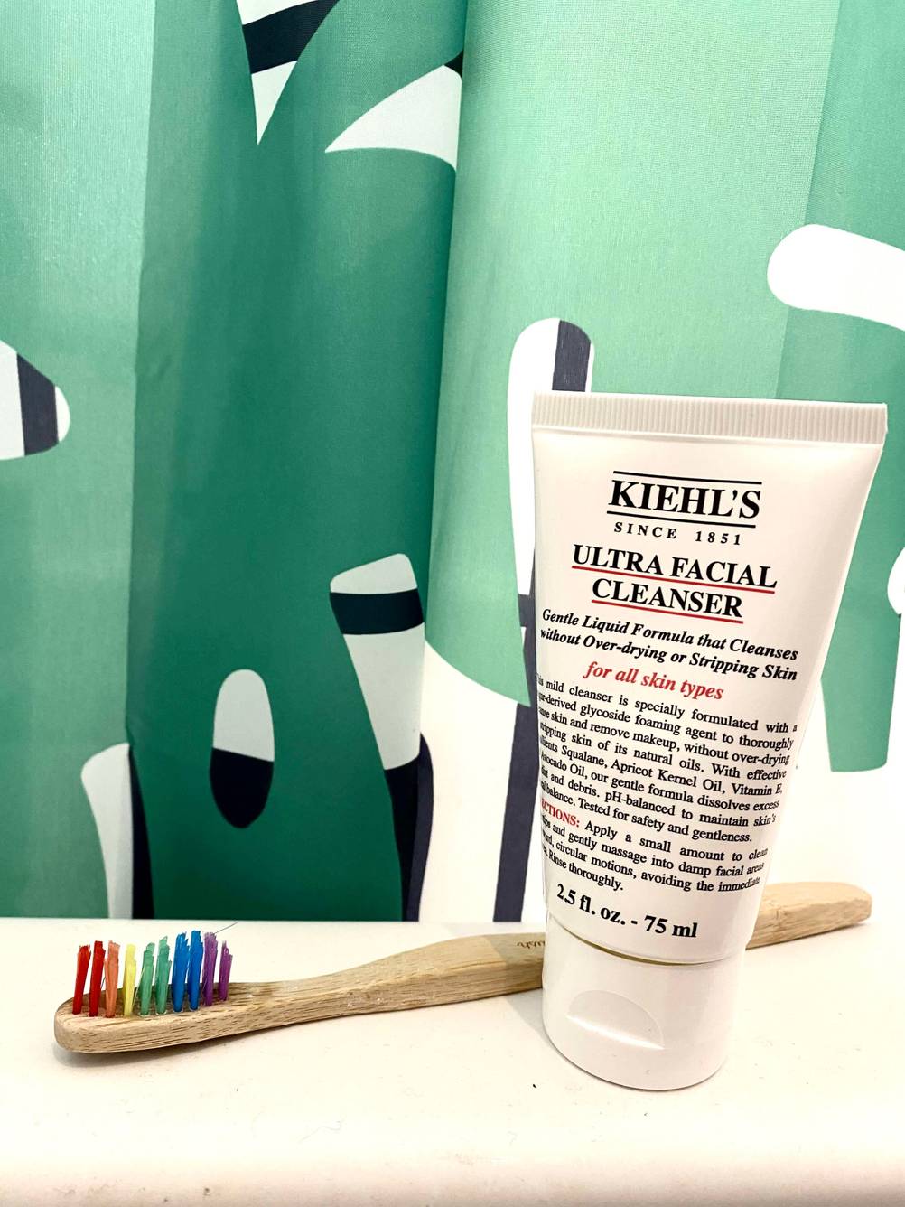 Getestet: Eine Tube Gesichtsreinigung steht vor einem Duschvorhang neben einer Zahnbürste.