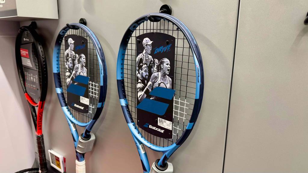 Mehrere getestete Babolat-Tennis-Schläger hängen an einer weißen Wand.