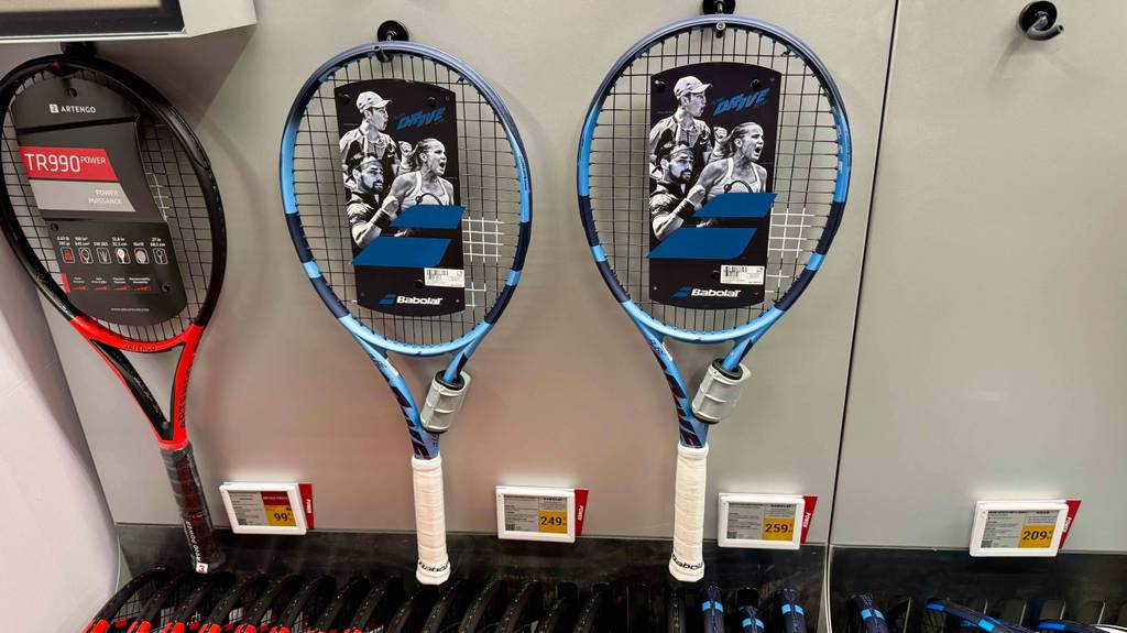 Getestete Babolat-Tennis-Schläger befinden sich im Geschäft an einer weißen Wand.