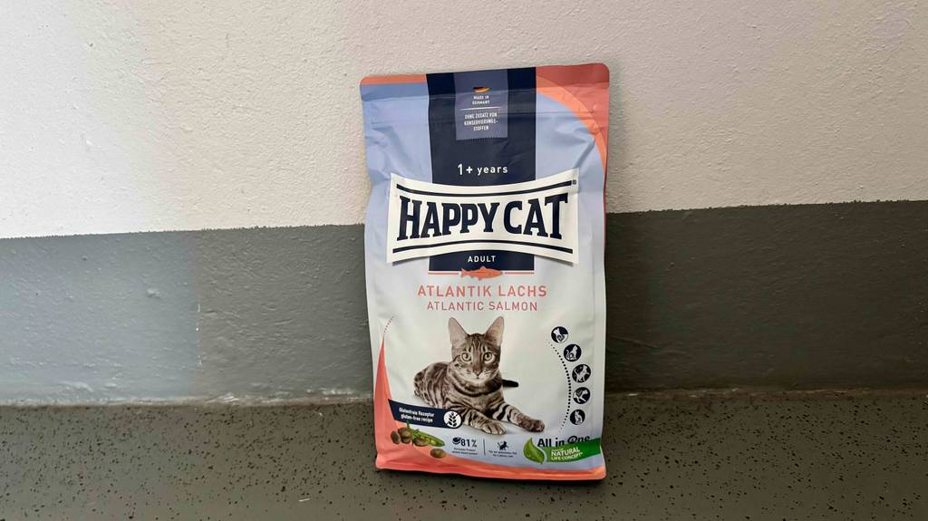 Eine Portionstüte inklusive getestetem Happy Cat Katzenfutter steht vor einer weißen Wand.
