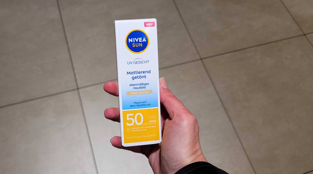 Eine Hand hält die getestete getönte Sonnencreme hoch.
