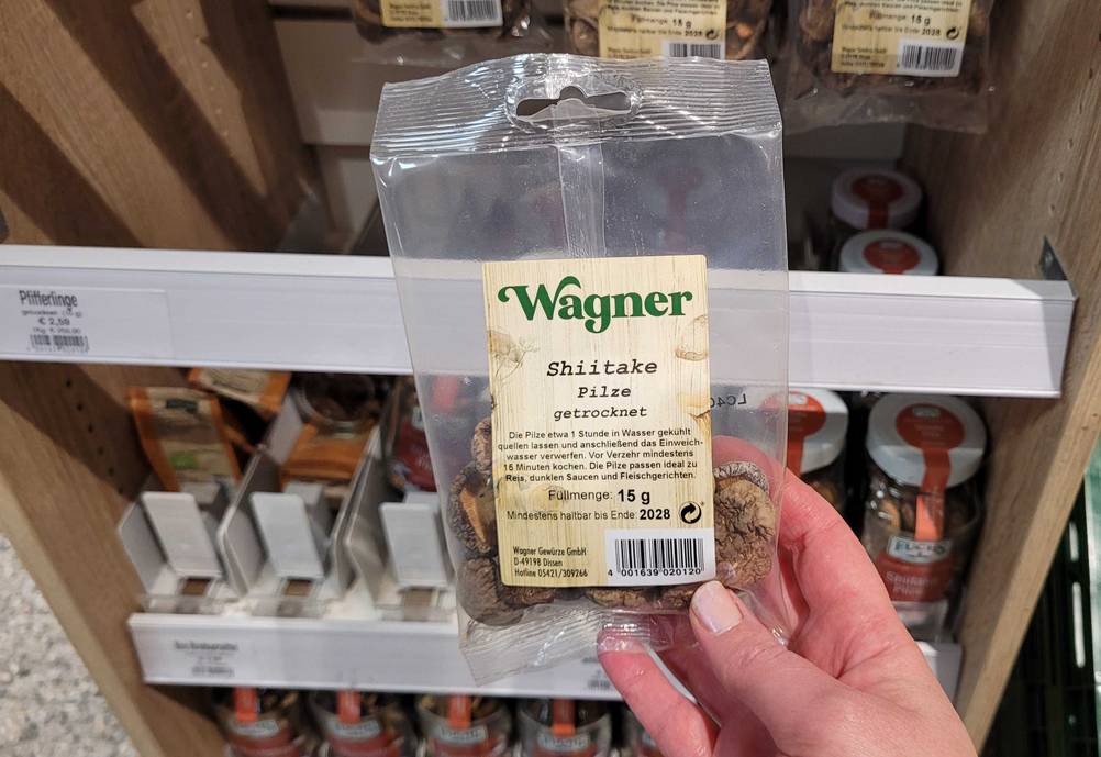 Eine Hand hält eine Packung der getrockneten Pilze im Test vor ein Regal.