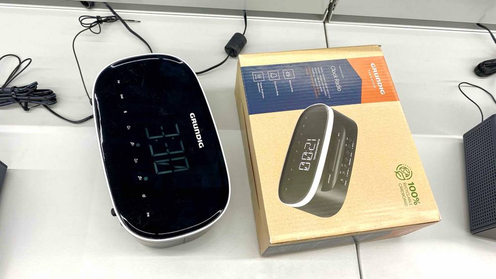 Ein getesteter DAB-Radiowecker neben der Originalverpackung auf einem weißen Verkaufsregal.