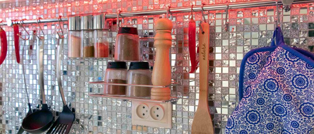 Nahansicht von Gewürzen und Küchenutensilien, die an einer Metallstange hängen.