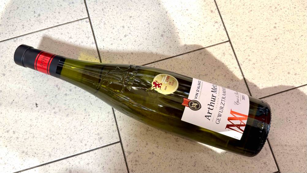 Auf einem Fließenboden liegt eine Flasche Gewürztraminer im Test.