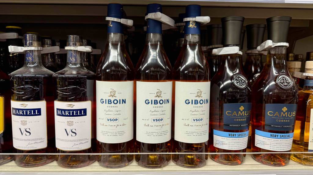 Cognac-VSOP im Test: Mehrere Flaschen stehen neben- und hintereinander zwischen anderen Sorten in einem Regal.