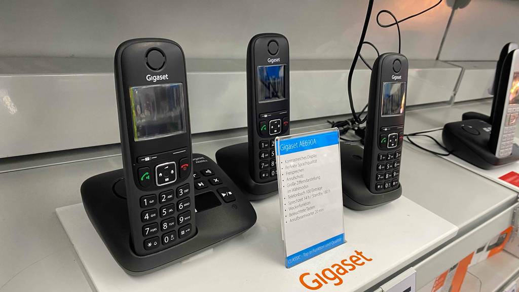Im Test: Gigaset Schnurloses Telefon-Trio aufgebaut auf einem weißen Regal mit Infotafel in Front.
