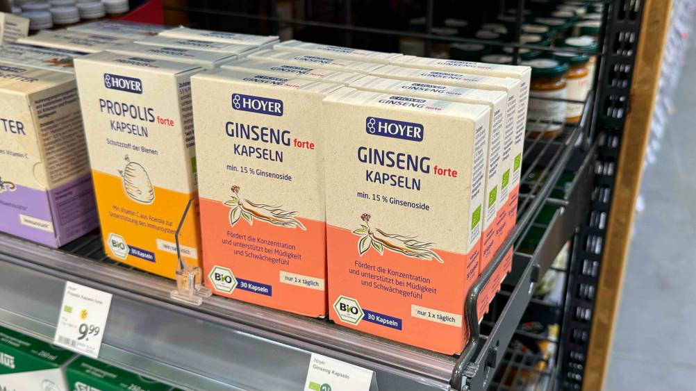Ginseng-Kapseln getestet: Mehrere Packungen stehen neben anderen Produkten in einem Regal mit Preisangaben.