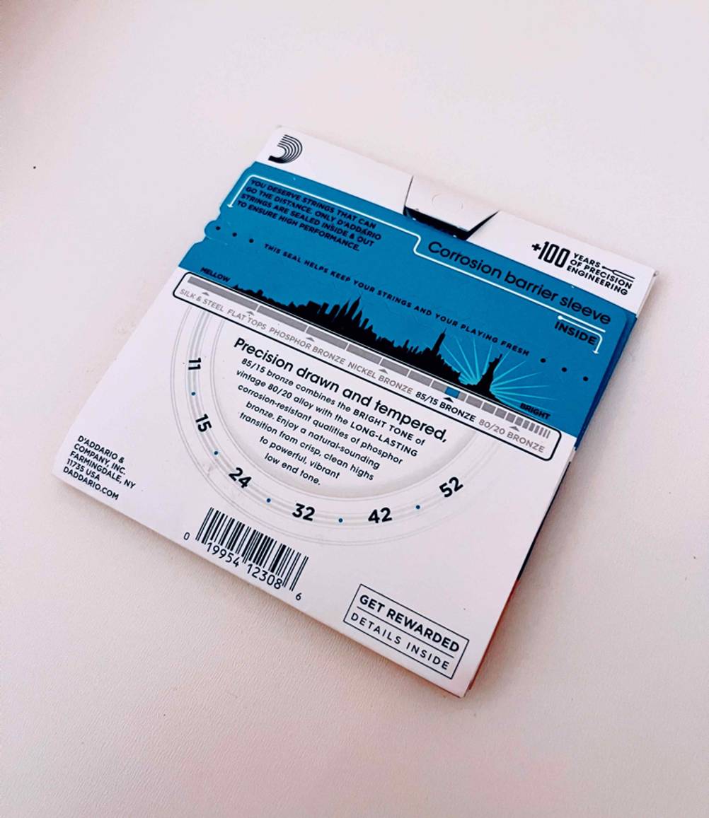 Gitarrensaiten im Test: Verpackung mit Gitarrenseiten liegt auf hellem Untergrund.