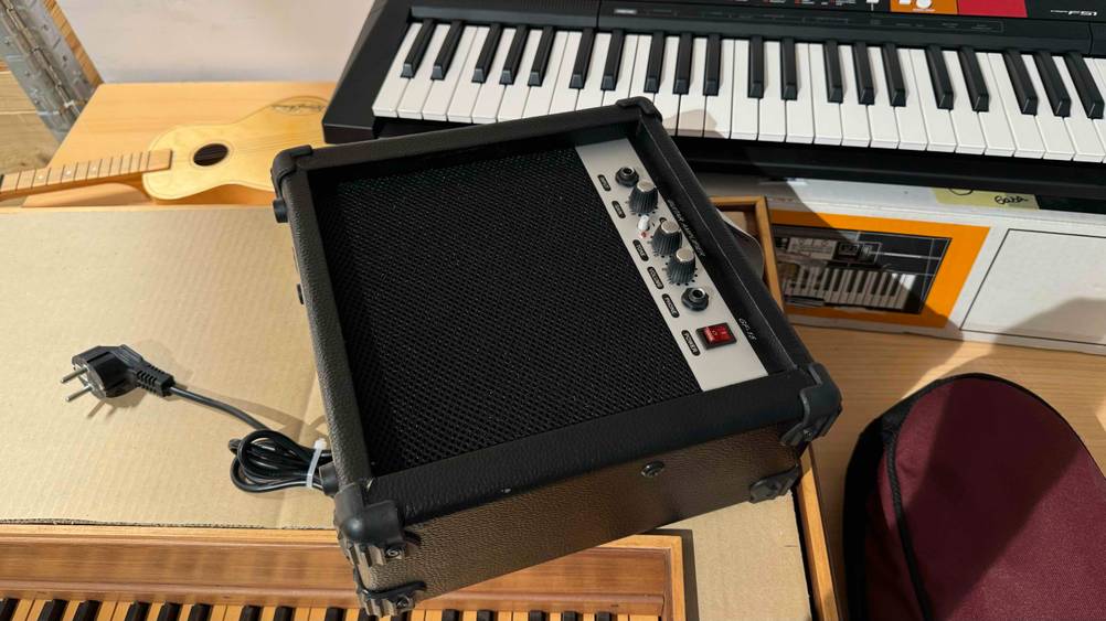 Ein Gitarrenverstärker im Test liegt auf einem Karton vor einem Keyboard.