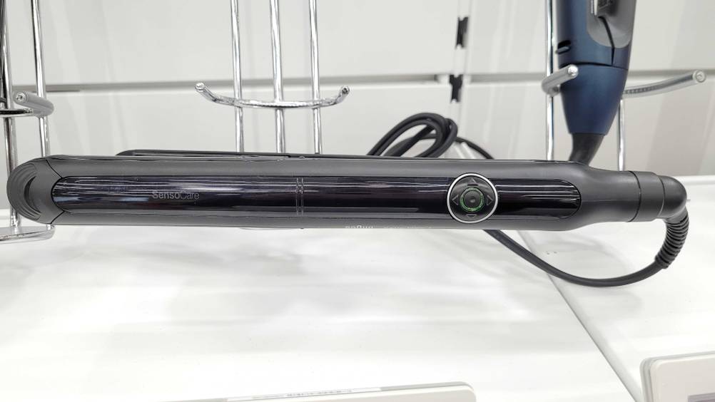 Getestet: Ein Glätteisen horizontal auf einer hellen Fläche liegend.
