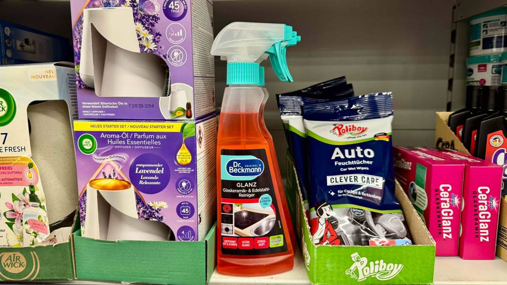 In einen Verkaufsregal stehen mehrere Flaschen Glaskeramik-Reiniger im Test neben anderen Produkten.