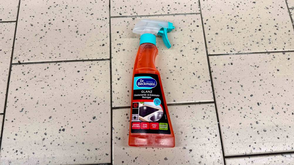 Eine Flasche des getesteten Glaskeramik-Reinigers liegt auf einem hellen Fließenboden,.