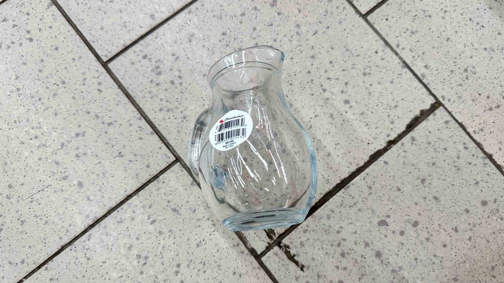 Auf einem Fließenboden liegt ein getesteter Glaskrug.