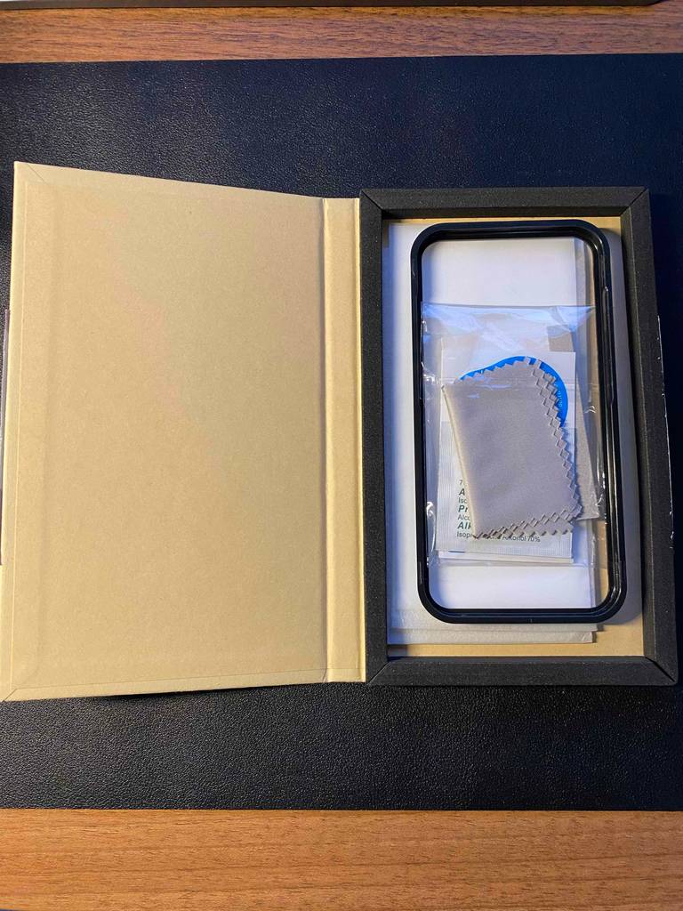 Geöffnete beigefarbene Verpackung inklusive iPhone 12 Pro Panzerglas im Test befindet sich auf einem schwarzen Untergrund.