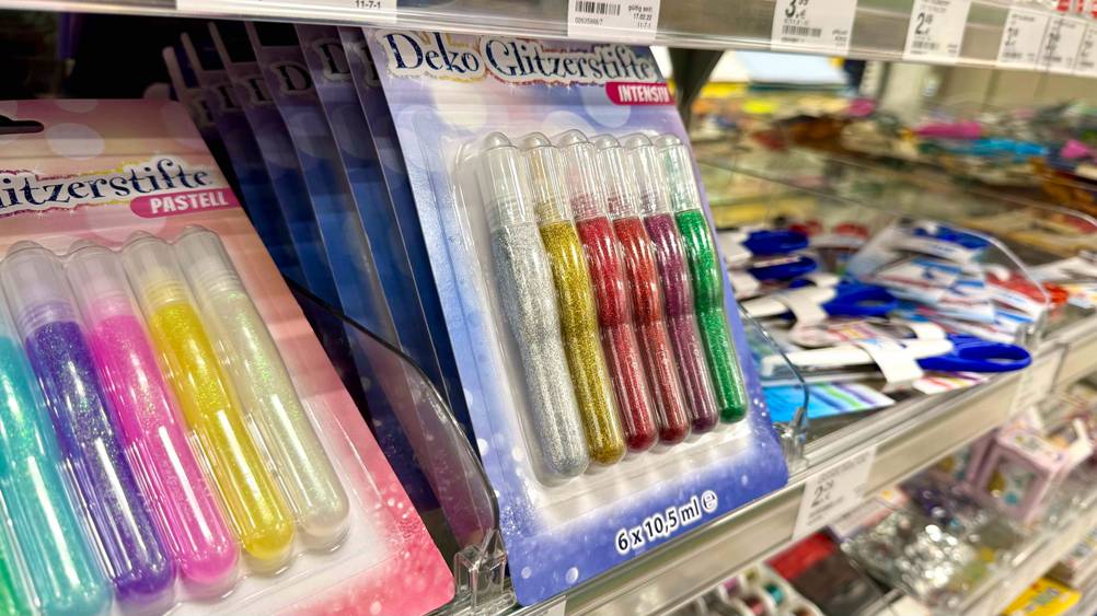 Seitenansicht mehrere Packungen der getesteten Glitzerstifte in einem Verkaufsregal.