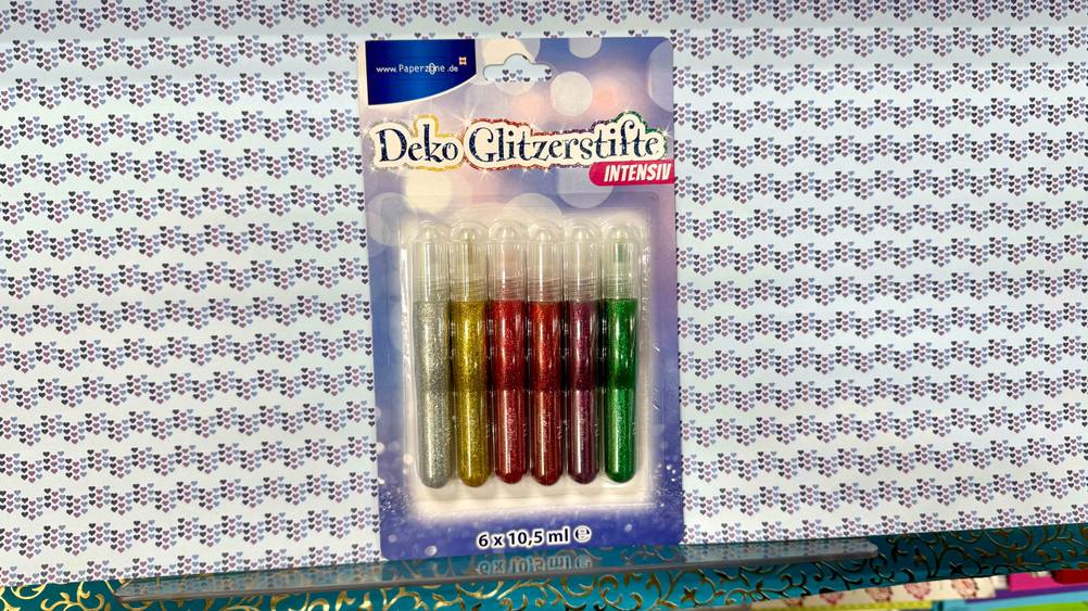 Auf einem Regal steht eine Packung der getesteten Glitzerstifte.