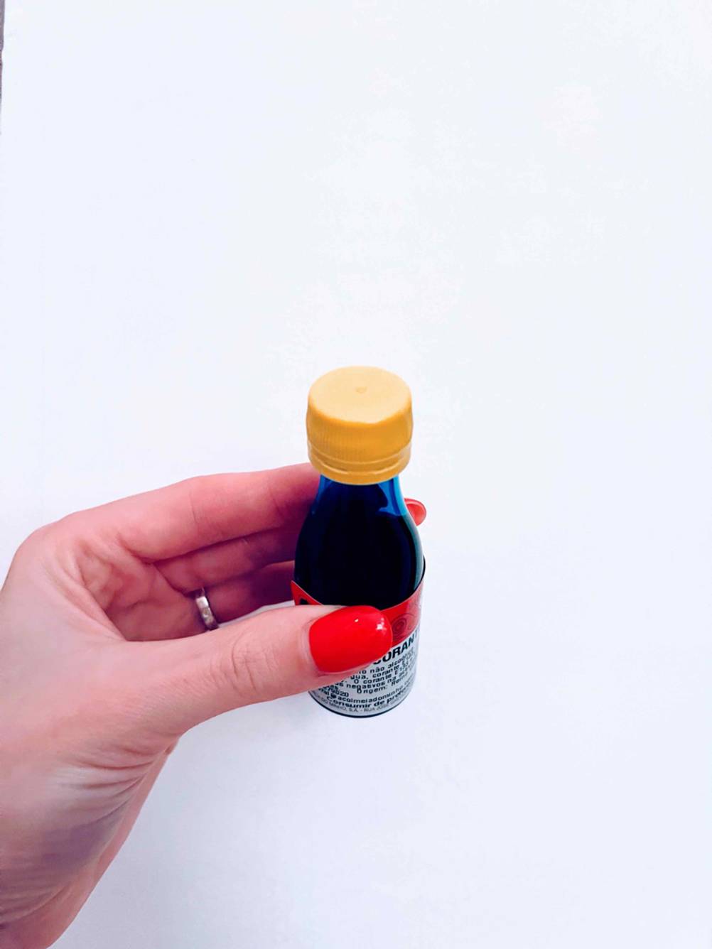 Getestet: Nahaufnahme des Deckels einer Flasche Lebensmittelfarbe die eine Hand vor eine helle Wand hält.