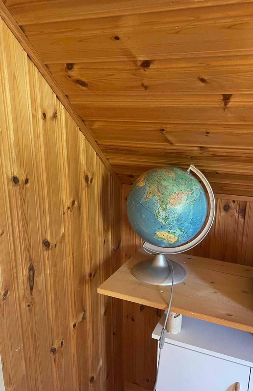 In einer Zimmerecke auf einem Holzbrett steht ein Globus im Test.