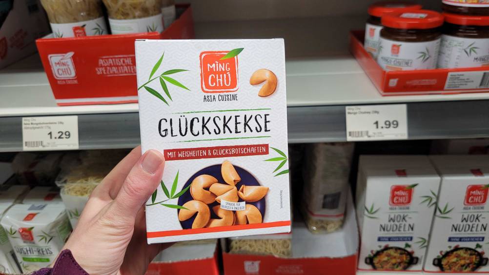 Getestet: Eine Hand hält eine Packung der Glückskekse vor ein Verkaufsregal.