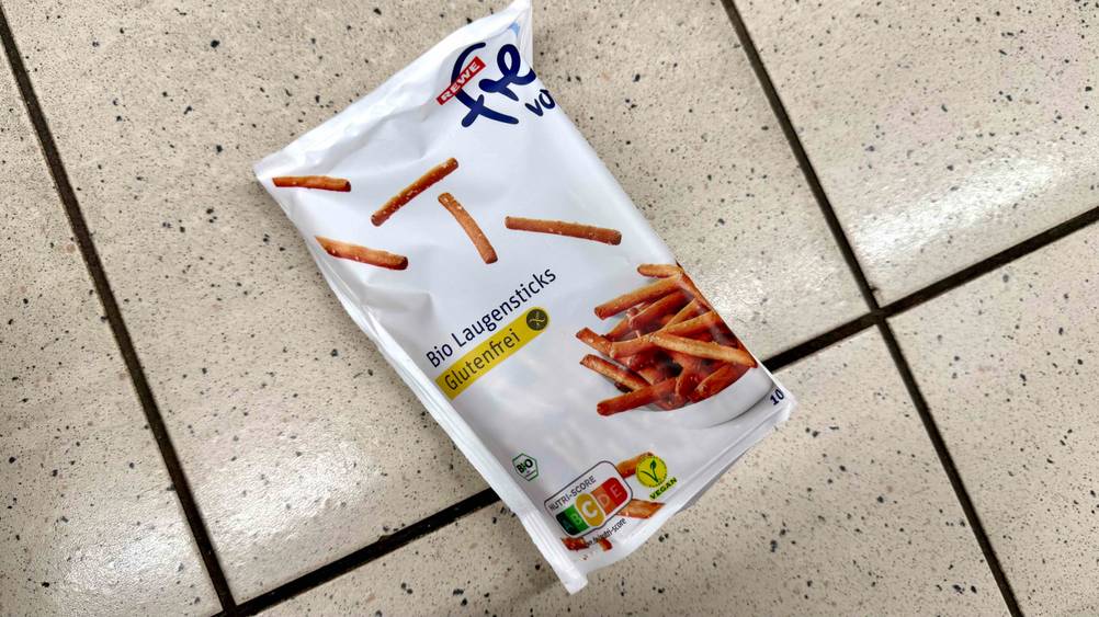 Auf einem Fließenboden liegt eine Packung der getesteten glutenfreien Snacks.