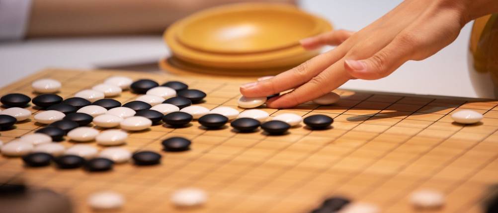 Go-Spiel-Test: Eine Hand wie sie einen Go-Spielstein setzt.