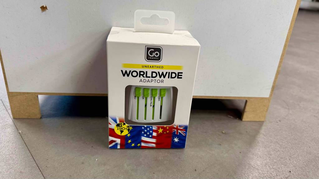 Im Test: Der Reiseadapter für weltweiten Gebrauch befindet sich in seiner Verpackung vor einer Verkaufspalette.
