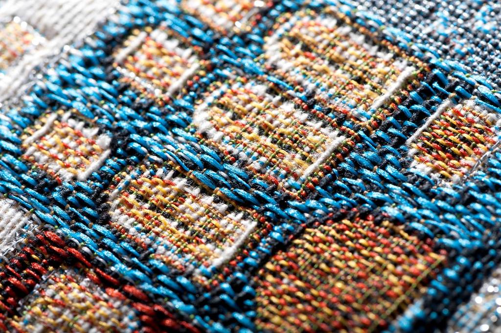 Gobelinstoff mit geometrischem Muster in blau, braun, organge, gelb und weiß.