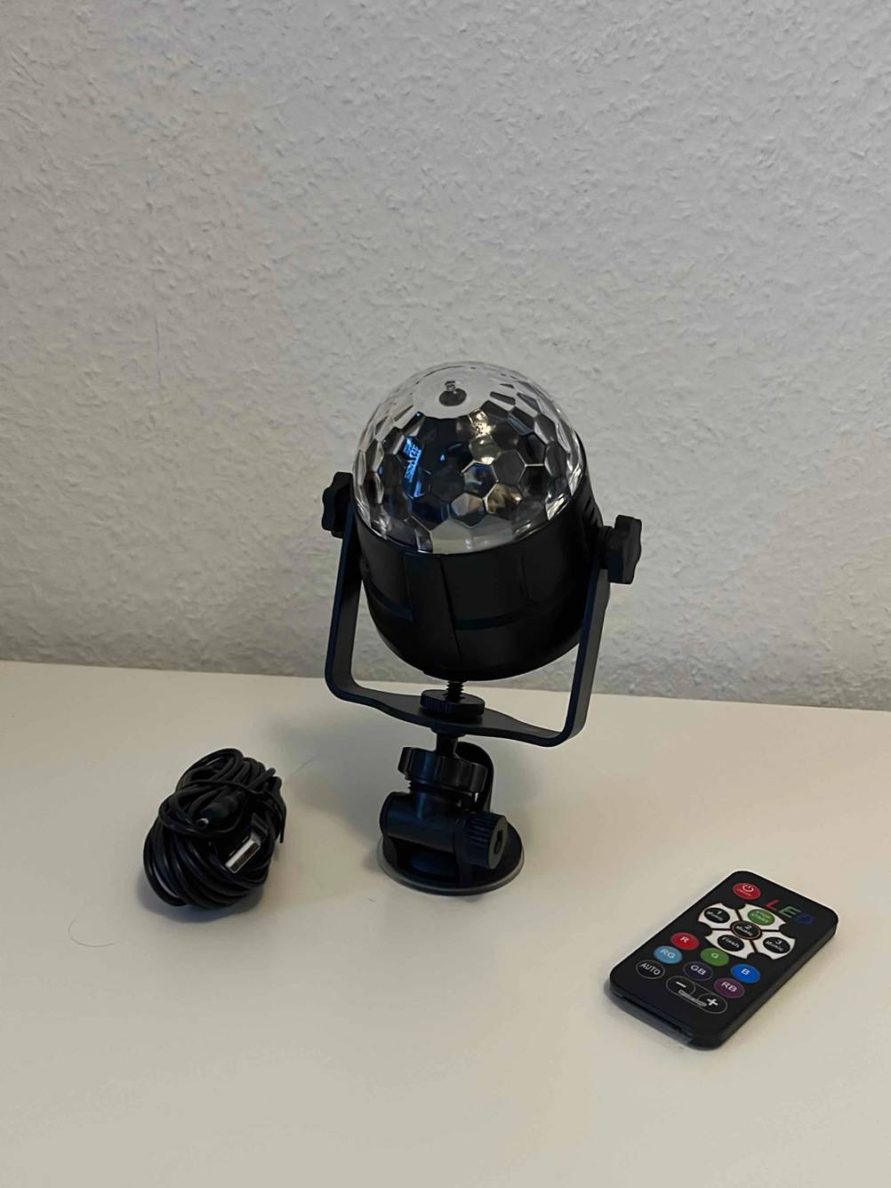 Im Test: Eine Discokugel für Kinder mit Ladekabel und Fernbedienung vor einer hellen Wand.