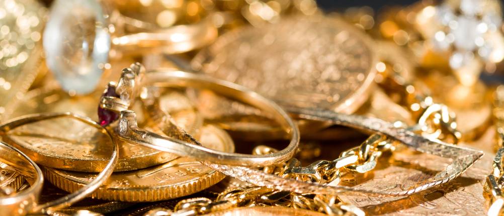 Goldener Schmuck und Münzen liegen aufeinander. 