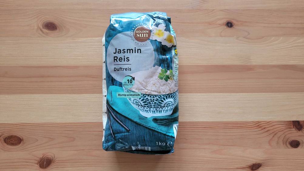 Eine Packung des getesteten Jasmin-Reis von vorne auf einer Holzfläche liegend.