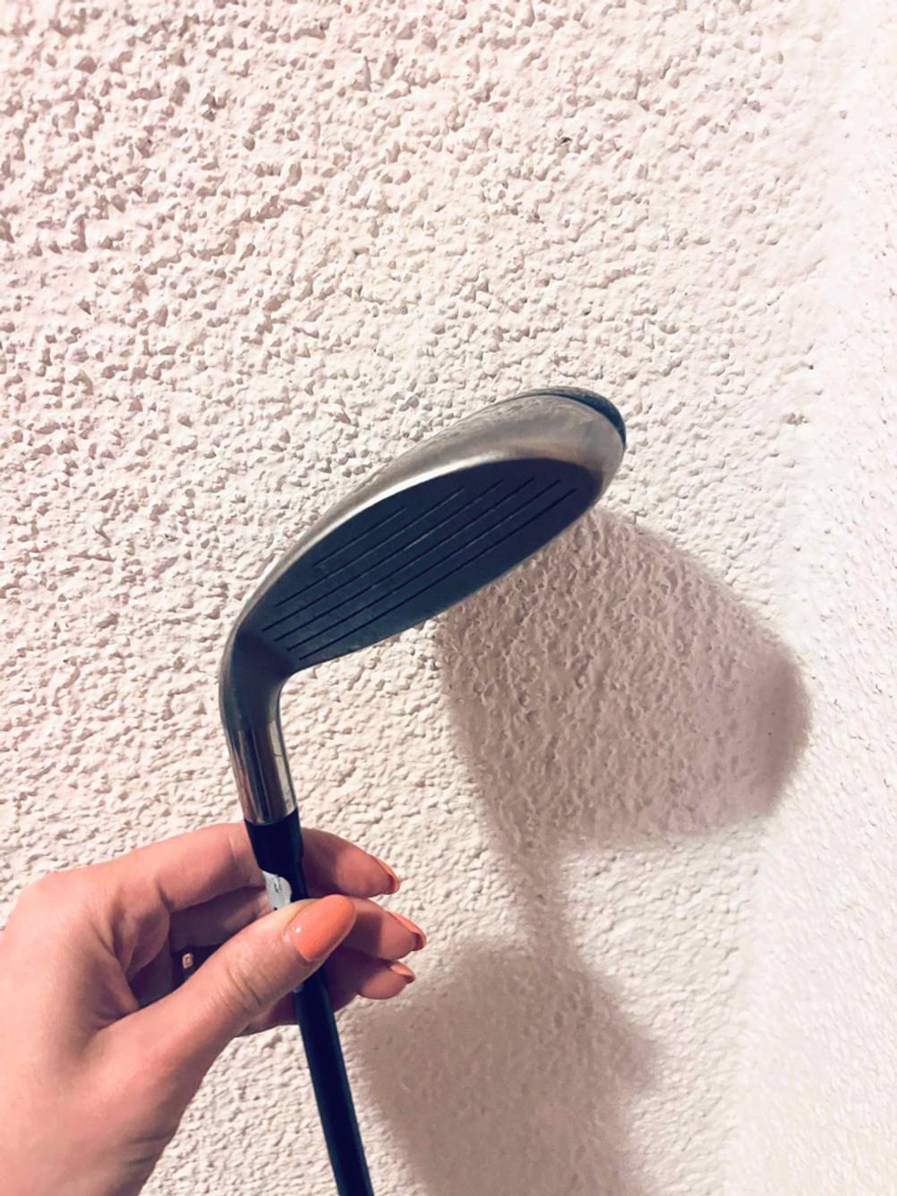 Golfschläger im Test: Eine Hand hält einen Schläger vor eine helle Wand.