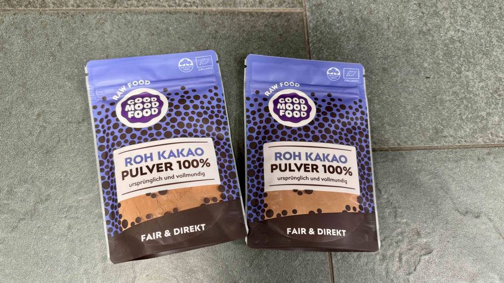 Getesteter Rohkakao liegt in zwei wiederverschließbaren Verpackungen auf einer grauen Fläche.