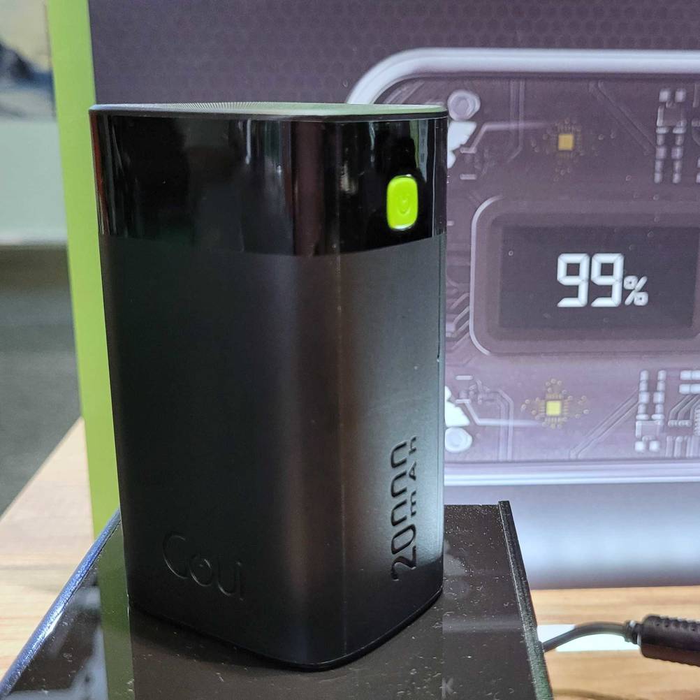 Die getestete Powerbank steht vor einem Plakat.